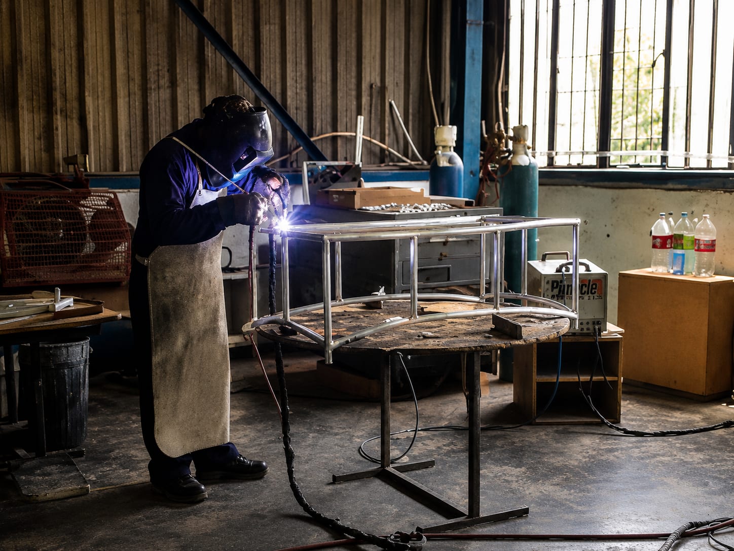 An artisan welding an aluminium furniture frame in the Mirage workshop
